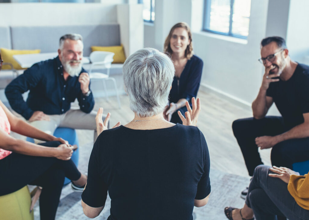 Business team sitting in circle and discussing The Imagine Well Being Story